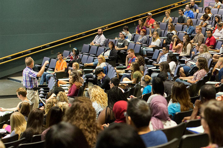 A faculty member lectures in a classroom auditorium.